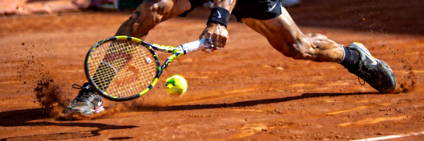 网球运动员在红土场地上滑步击球的动态瞬间